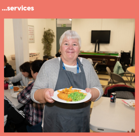 a photo of a women holding a roast dinner in a community centre