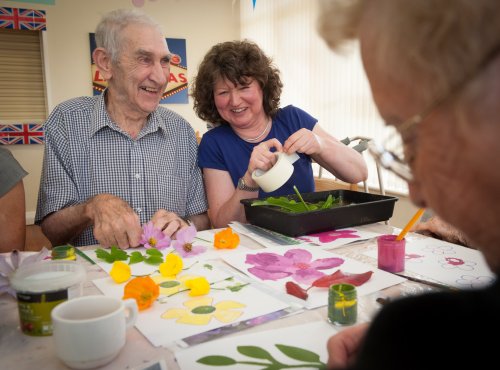Picture of elderly man and woman smiling while doing a craft activity.