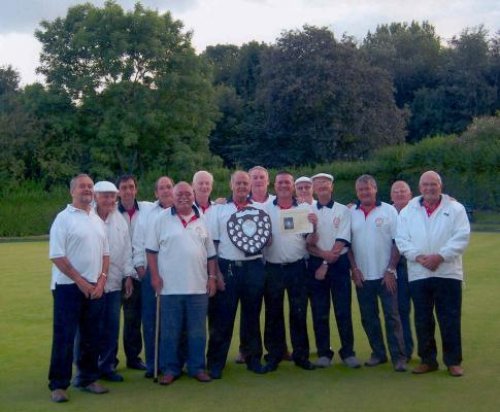 A group of the bowlers holding a shield trophy on the green