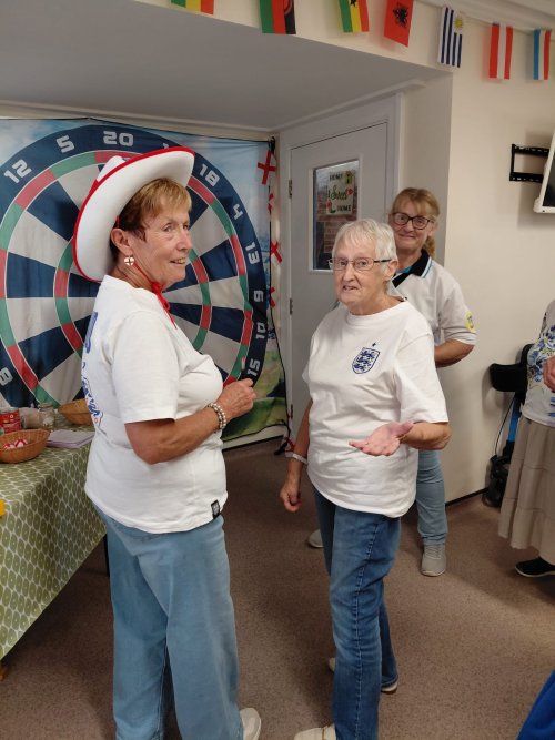 Older women playing darts in front of a large fabric darts board