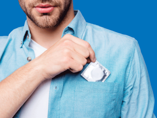 A close up of a man taking a condom out of his shirt pocket