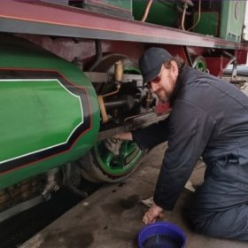 A volunteer cleaning parts of a steam train 