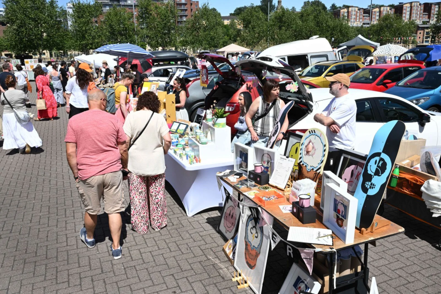 People browsing an art car boot fair in the sun