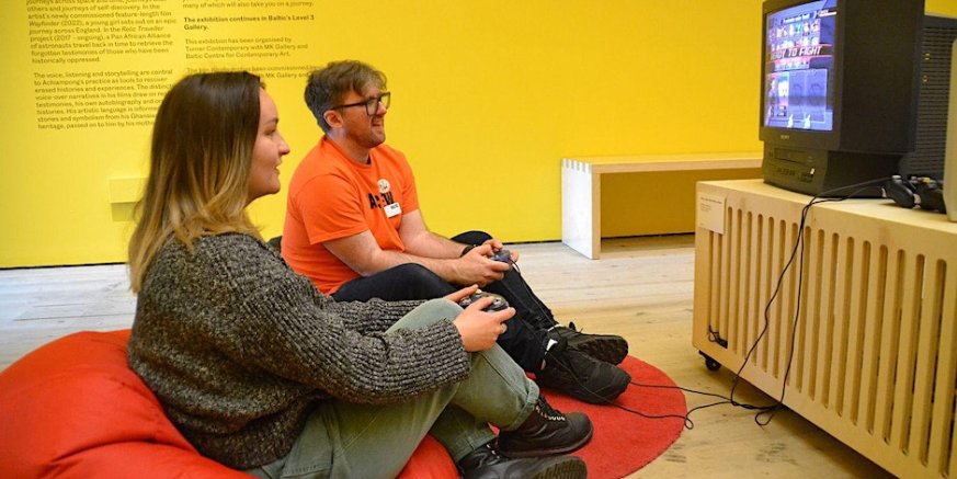 two people sitting on a bean bag playing a game on a TV