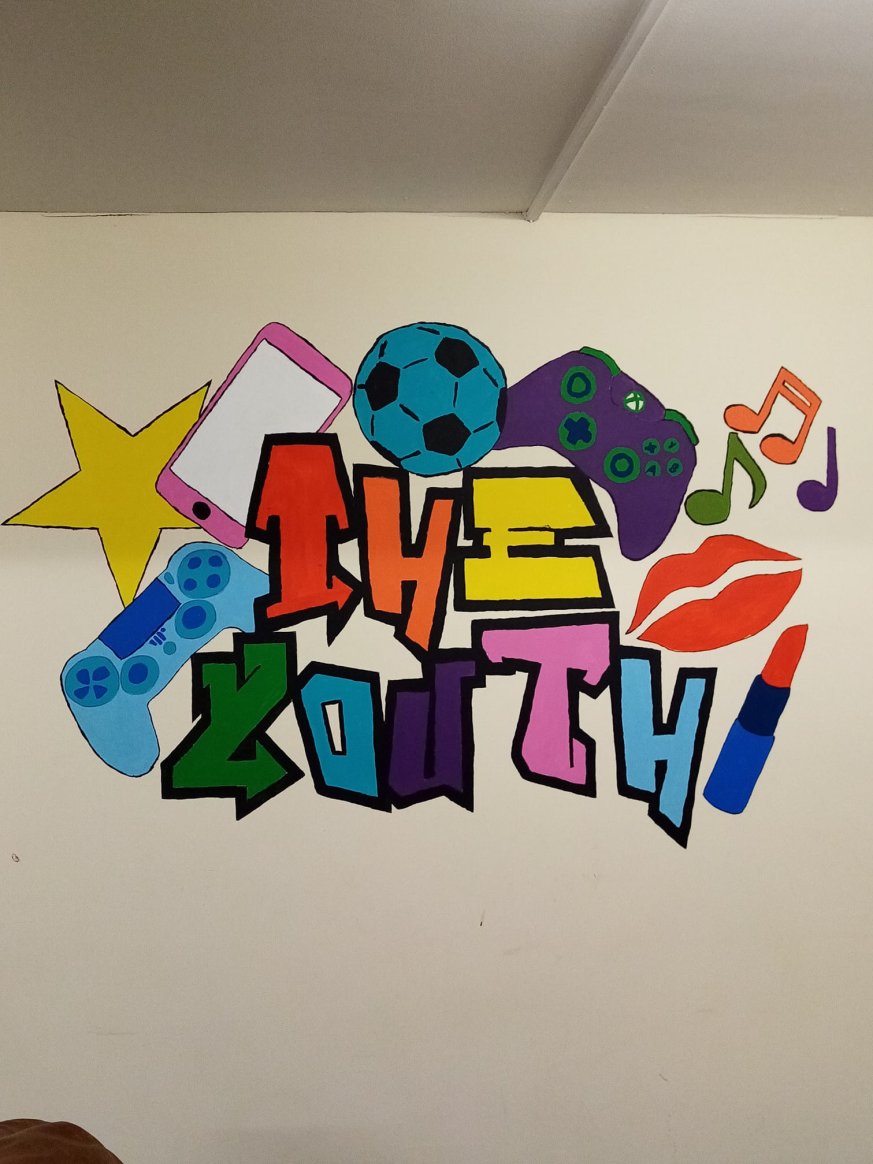 A mural designed by young people stating "the youth" surrounded by makeup, sports equipment and games consoles