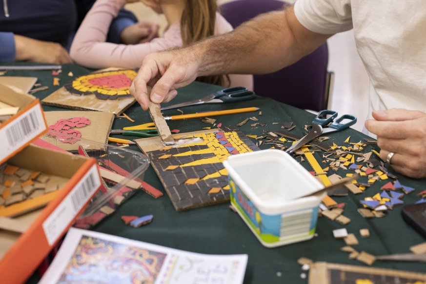 A photo of someone gluing on mosaic pieces on a board.