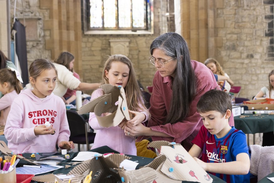 A photo of a woman with three children. They are making various crafts on the table in front of them.