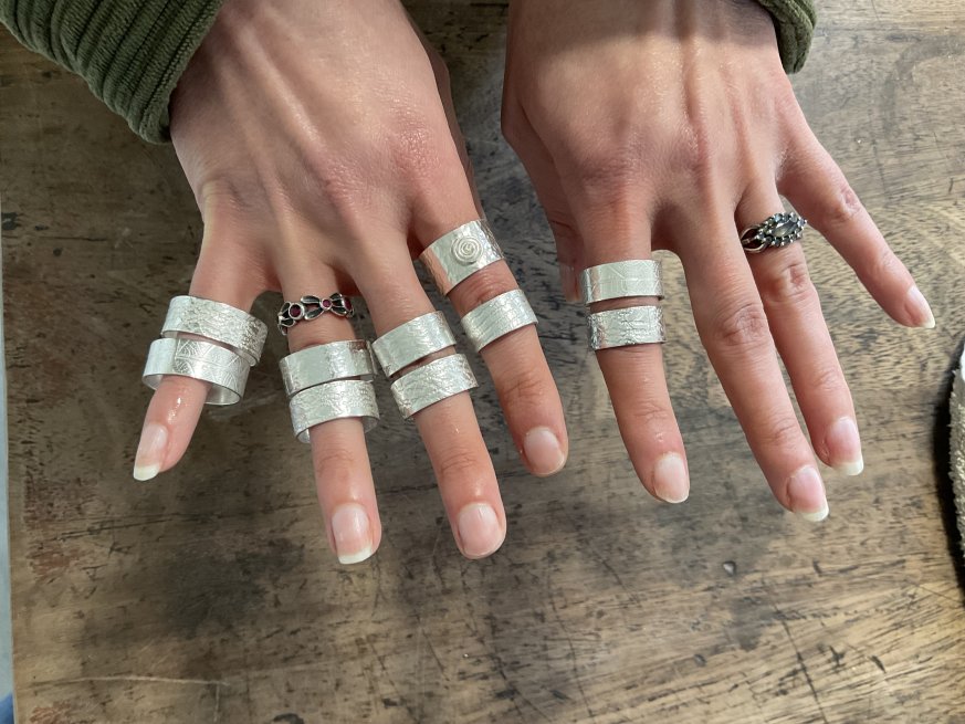 Two Hands showing 10 Silver Rings made in a Ring Making Workshop