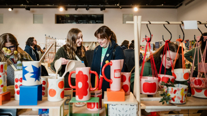 People are browsing a stall filled with ceramics at a makers market