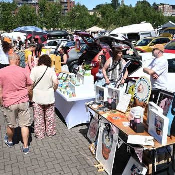 People browsing an art car boot fair in the sun