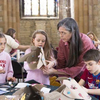 A photo of a woman with three children. They are making various crafts on the table in front of them.