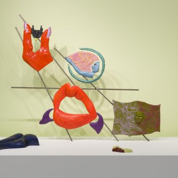 Installation view of Jala Wahid's sculpture with brightly coloured resin and fibreglass elements including bright red lips and a red hand with purple nails