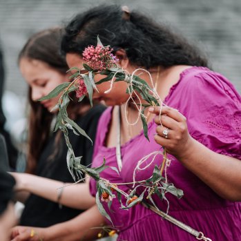 A person wearing pink holds a flower crown 