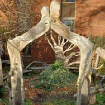 A photo of the library garden. There is a tall, wooden arch in the middle of the garden with benches in a circle.