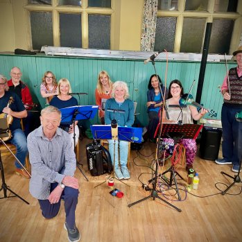 The Redheughers Ceilidh Band sitting with their instruments ready to perform