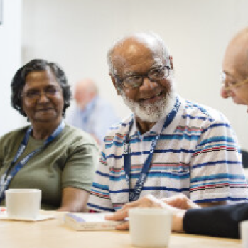 Three diverse committee volunteers sitting at a table having a friendly discussion