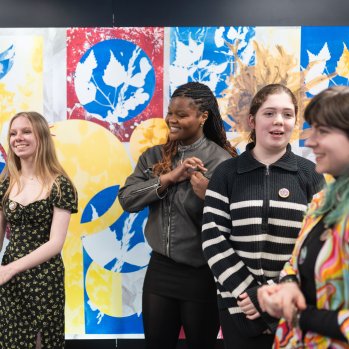 A group of young artists standing and smiling in front of an artwork they created