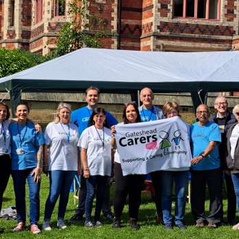 Members of Gateshead carers Association holding their banner in front of a gazebo 